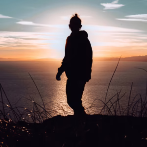 silhouette of man standing on hill during sunset