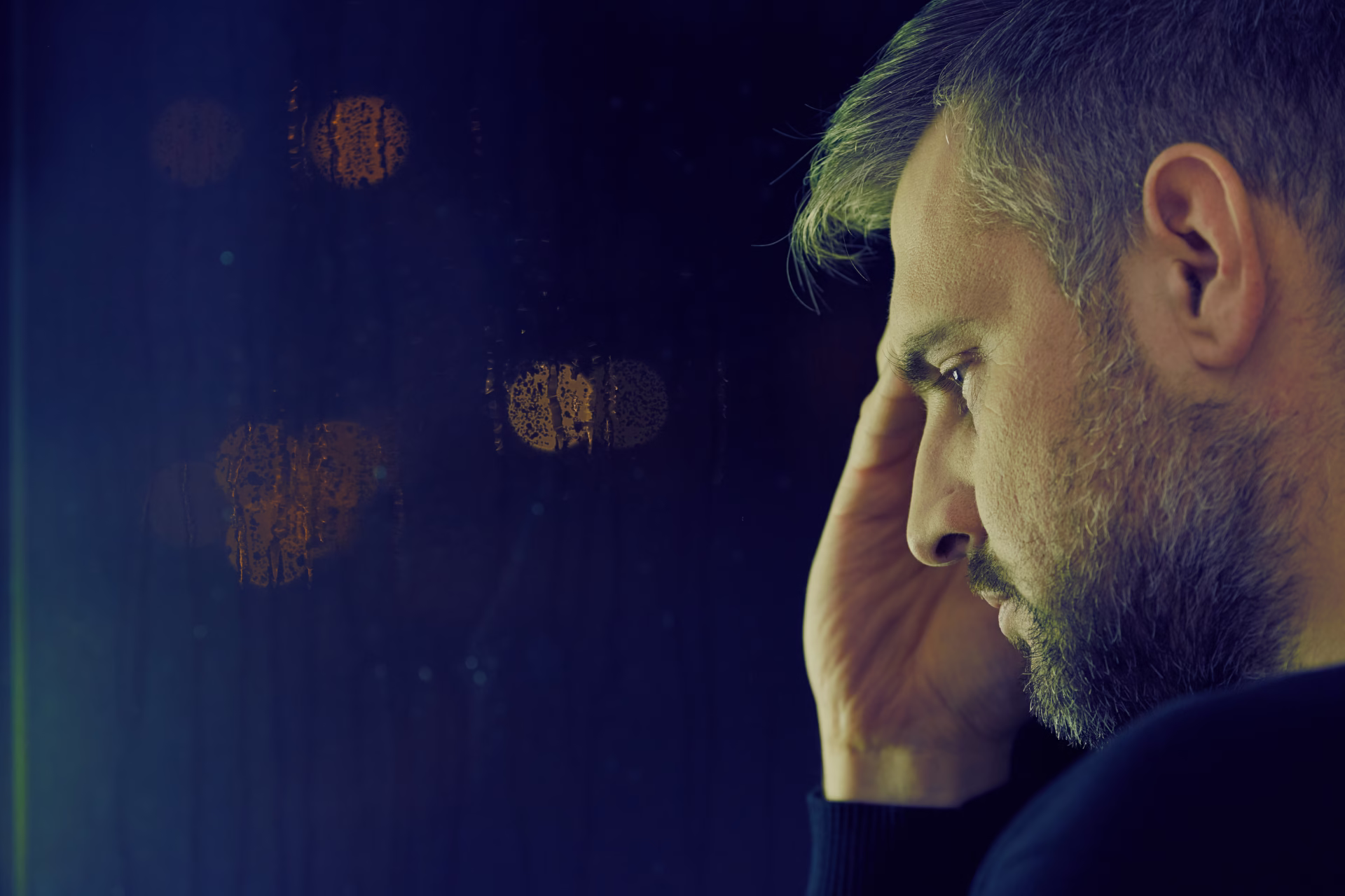 A person sits alone near a window in soft morning light, reflecting on personal development after job loss.