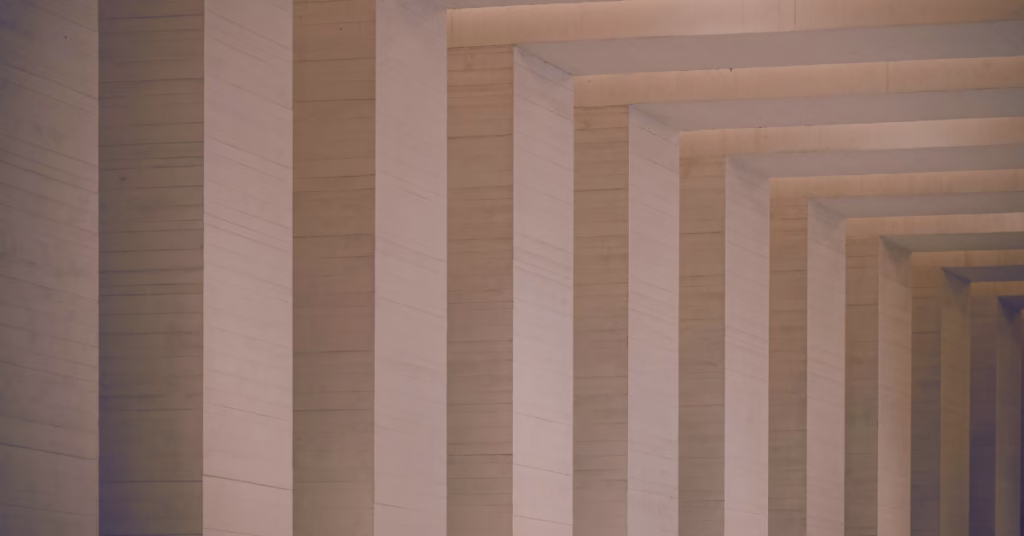 Abstract layers of structure beneath a lit surface, representing the hidden belief architecture operating beneath conscious thought.